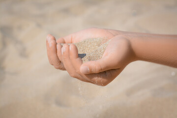Child pouring sand from hands outdoors, closeup. Fleeting time concept