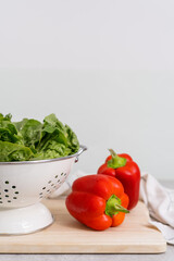 red bell pepper and green salad leaves at kitchen with white wall