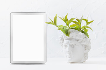 Brainstorming concept with spring young green twigs as wreath of thoughts over head of white antique statue David in intense thinking, creativity process, blank digital tablet mockup for text.