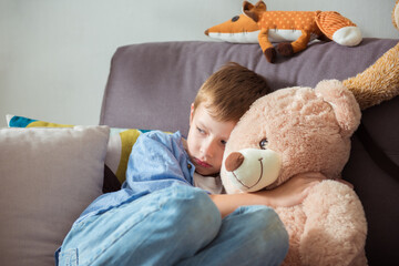 Little boy hugs his teddy bear, feels lonely. Teddy bear is ready to be the best friend