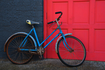 Fototapeta na wymiar Old blue bicycle in front of a red door