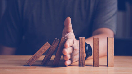 Risk assessment and management concept. Man's hand prevent or protect the domino wood block like risk that will impact or effect their business with good risk assessment. - obrazy, fototapety, plakaty