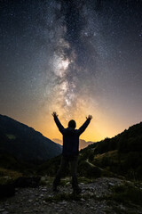 silhouette of a person in the mountains under the milky way