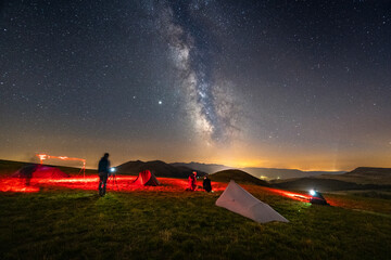 People photographing the milky way in nature. People with milky way, in the mountains. Light painting in a nightscape