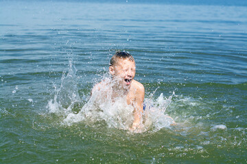 A boy plays in the water, splashes in the river