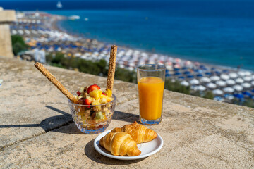 Orange juice with a croissant and fruit salad for breakfast in a hotel room on a balcony...