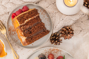 Delicious semi-naked chocolate cake with caramel topping and decorated with blackberries and raspberries. Light background