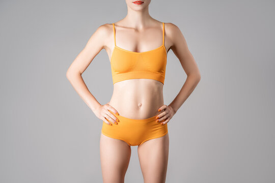 Slim woman in yellow underwear on gray background
