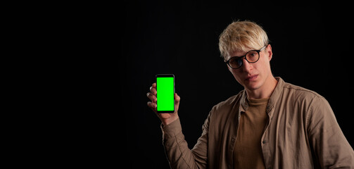 guy 25 years old holds in his hand a smartphone mockup with a chroma key screen on a black...