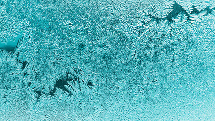 Frosting on a window glass in winter. Weather forecast. Turquoise tinted wallpaper. Abstract nature season background. Christmas theme