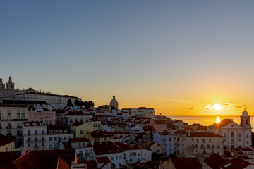 Typical cityscape of Lisbon, Sun rising in the morning with orange brick roof top of buildings and housing with harbor view, Narrow houses between small street in coastal of atlantic, Lisbon, Portugal