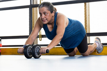 Woman strengthening her body by using the abdominal wheel
