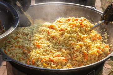 Cooking pilaf in a large cauldron over an open fire. Street food