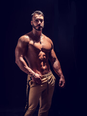 Obraz na płótnie Canvas Shirtless muscular male bodybuilder in studio shot on black