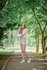 beautiful fair-haired girl on a bicycle with flowers. Hydrangeas.