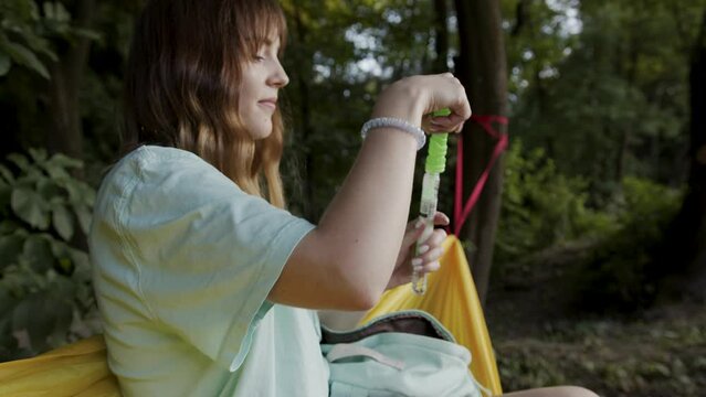 Girl inflates soap bubbles outdoor in park. Golden hour sunset light. Beautiful caucasian young girl.
