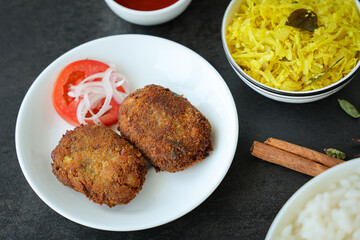 beef or chicken cutlet, tomato sauce Kerala South India. hot and spicy tea time snack on white plate, dark black background. fried meat of veal, mutton or fish. Top view Indian snack non veg food