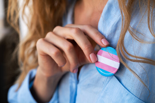 Woman with transgender badge puts on a shirt