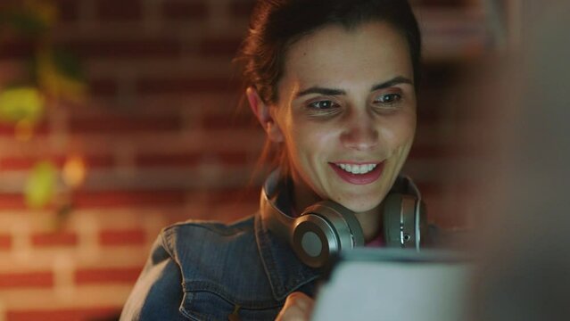 Woman, tablet and digital marketing collaboration in night office with teamwork, employee and worker in creative office. Smile, happy and talking designer with music headphones, seo or iot technology