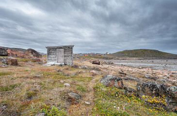 Fototapeta na wymiar A shed and a distant view of the hamlet of Apex on the edge of the Arctic Ocean in Nunavut
