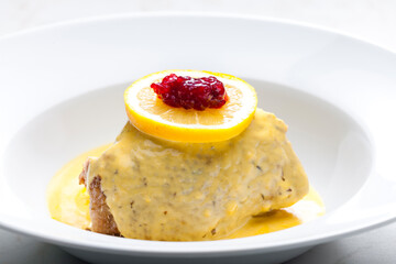 poultry meat with creamy sauce served with lemon and cranberries