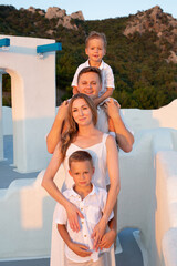 Fototapeta na wymiar Happy family with children on vacation in Santorini, Greece at sunset.