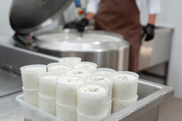 Cooking cheese from a private cheese factory. Man checks consistency of raw materials with a spoon