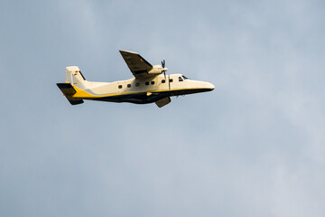 Two-engine gray yellow plane flying in blue sky