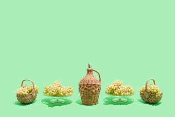 Aesthetic composition of green (white, Victoria) grapes, vintage braided wine bottle and wicker...