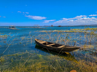 Obraz premium Wooden boat moored in a lake with captive fish farming structure