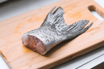 Closeup of raw fish tail on wooden board