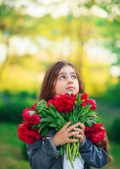 Naklejka premium Little cute girl with peony flowers. Child playing in summer garden. Kids gardening. Children play outdoors. Toddler kid with flower bouquet for birthday or mother s day.