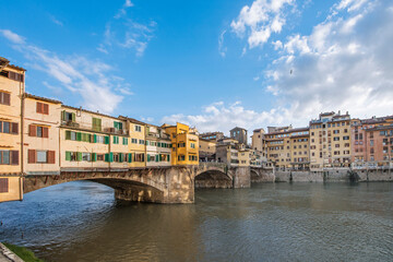 Fototapeta na wymiar The Ponte Vecchio, Old Bridge, is a Medieval stone closed-spandrel segmental arch bridge over the Arno River, with shops built along it; as jewelers, art dealers and souvenir sellers. Italy, 2019