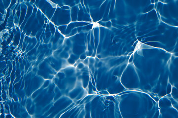 Bluewater waves on the surface ripples blurred. Defocus blurred transparent blue colored clear calm water surface texture with splash and bubbles. Water waves with shining pattern texture background.