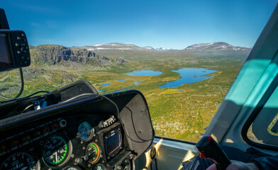 View from cockpit of small helicopter on lakes and mountains in vast Arctic landscape. Risjakjavrre...