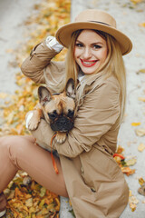 Young blonde girl holding a little puppy french bulldog