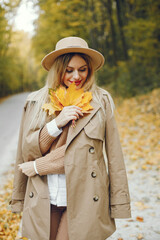 Portrait of a young blonde girl in a beige hat outdoors on autumn