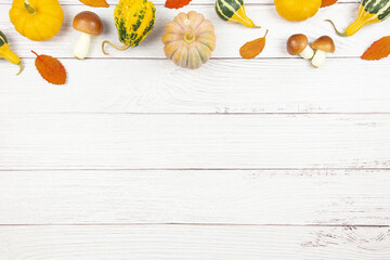 Fall flat lay with colorful pumpkins, mushrooms and fallen leaves on white wooden background. Autumn mockup with decoration. Top view. Copy space.