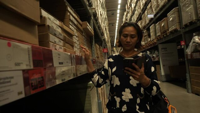 An Asian woman checks the price of furniture found in a warehouse