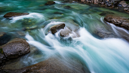 Naklejka na ściany i meble turquoise water flowing over rocks - long exposure