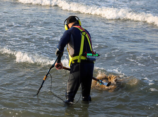 Researcher man white recovering lost items on sea on on the beach in summer