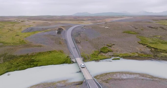 Aerial view of white car driving over one lane bridge on Kjolur road in the highlands of Iceland.