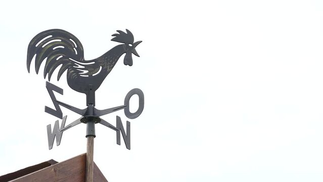 a chicken compass indicates the direction of the wind on the roof of a house with a clear sky