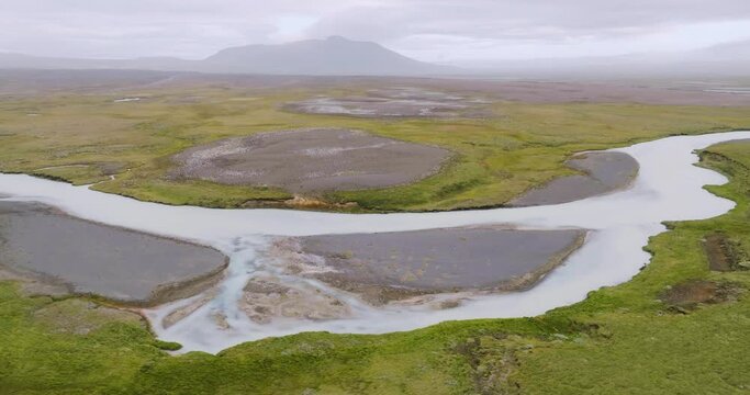 Aerial view, flying sidewards, of winding river Sanda with sandbanks in the desolate highlands of Iceland.