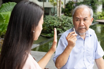 woman try to stop an old senior man from smoking, concept of quit smoking, no smoking, smoking reduction, lung cancer awareness month