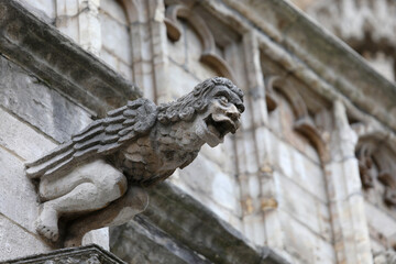 Monstrous statue with almost human features called gargoyle on the historic building