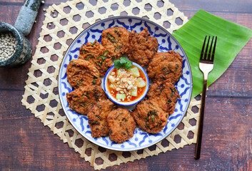 Thai fish cake or Fish cake ball - Thai food called Tod Mun Pla Krai with sweet chili dipping sauce at top view on wood table