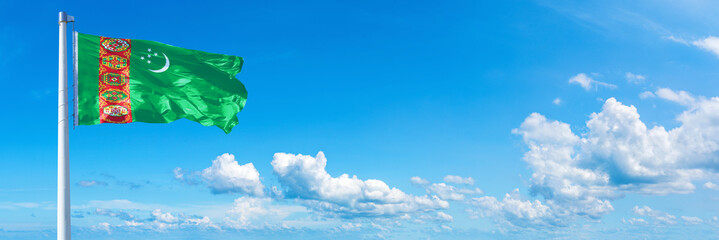 Turkmenistan flag waving on a blue sky in beautiful clouds - Horizontal banner