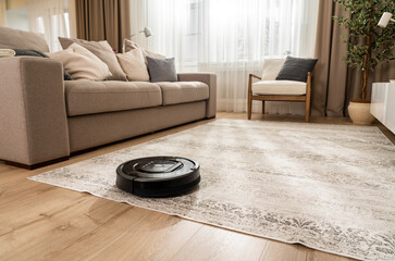 Vacuum cleaner robot working on carpet in new living room in light beige and gray colors