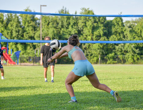 Girl Passing The Ball During A Coed Grass Doubles Game Of Volleyball On A Sunny Afternoon